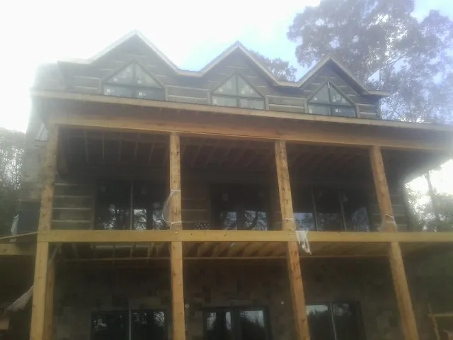 Dormers and porch framing on a large log home under construction — Roof Coating work by our crew in Galvin