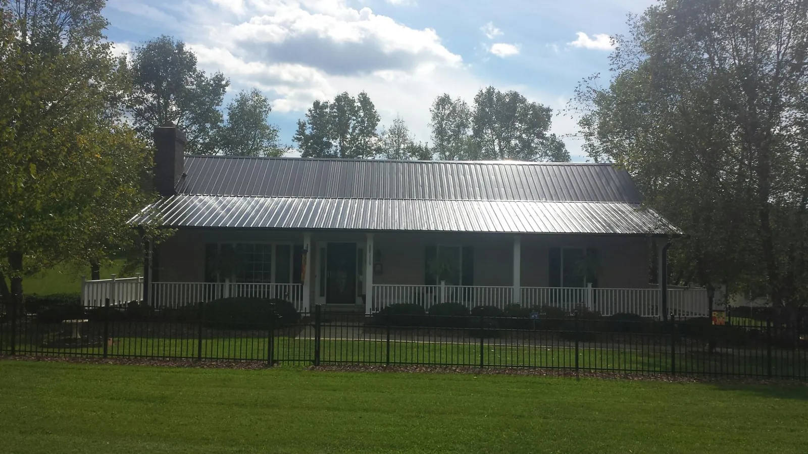 Gray metal roof on a brick ranch with a full width front porch — Gutter Guard Installation work by our crew in Galvin
