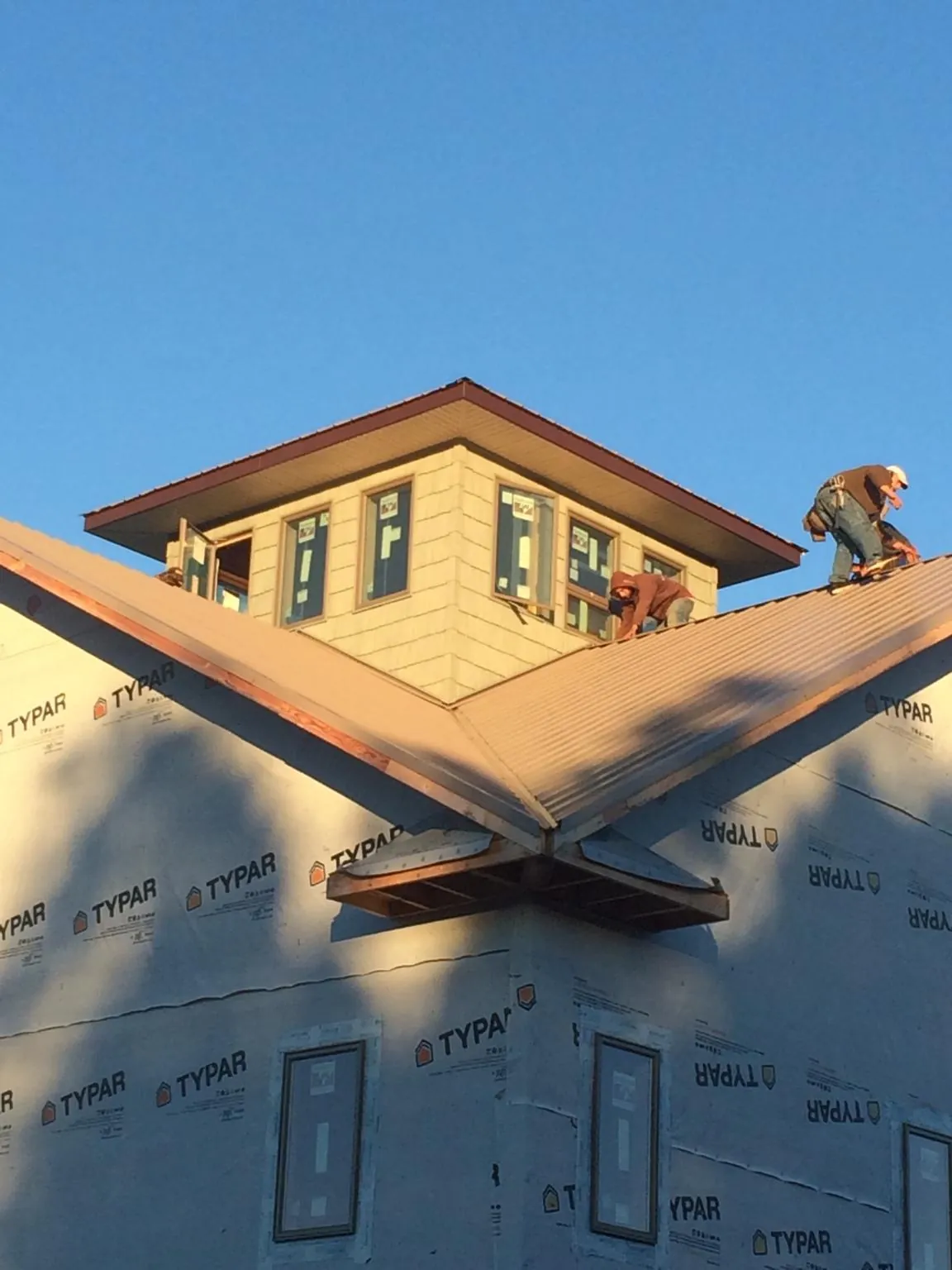 Roofers working around a rooftop cupola on a new metal roof at sunset — Roof Waterproofing in Galvin by Roofing Brothers